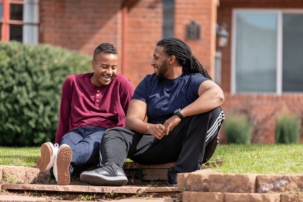 Big and Little sitting on curb smiling